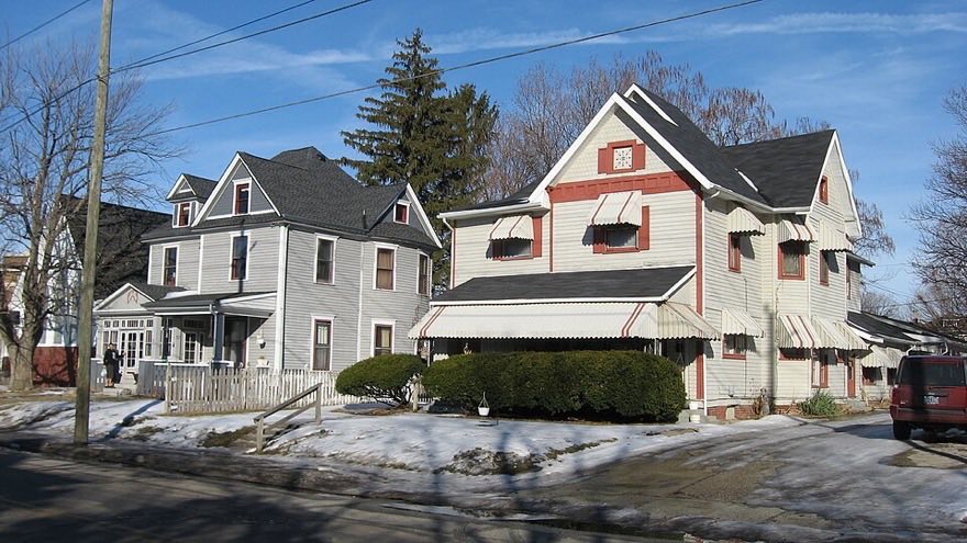 Two large timber-framed Victorian houses with steep gables and awnings on Ritter Avenue in the Irvington Historic District, Indianapolis, in winter